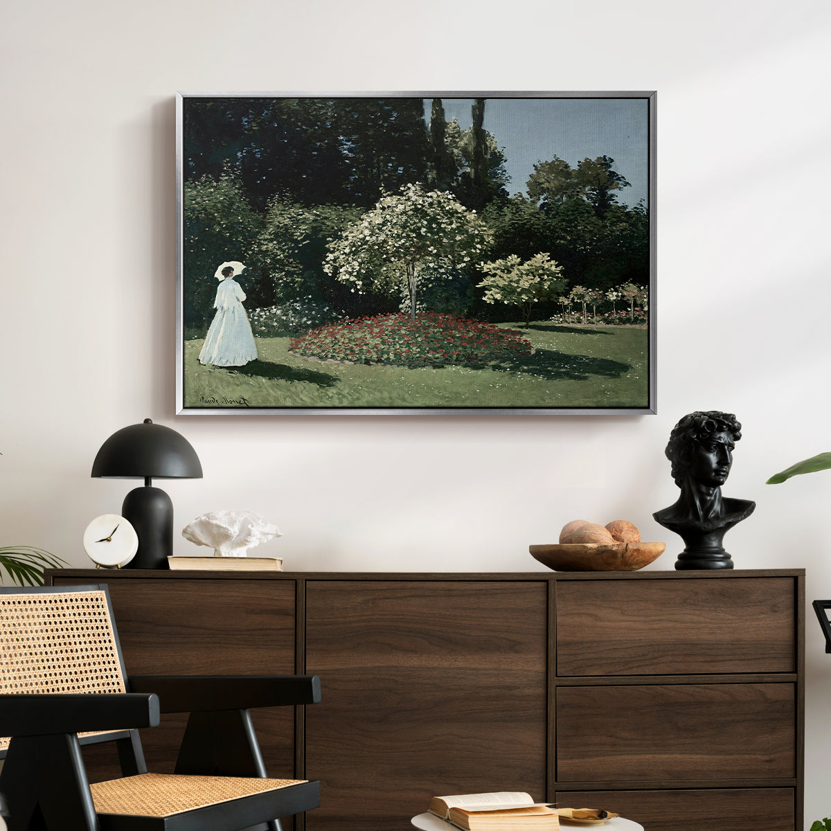 Woman in the Garden, Sainte-Adresse, 1867 by Claude Monet displayed in a silver floater framed canvas above a dark wood credenza in an entryway.