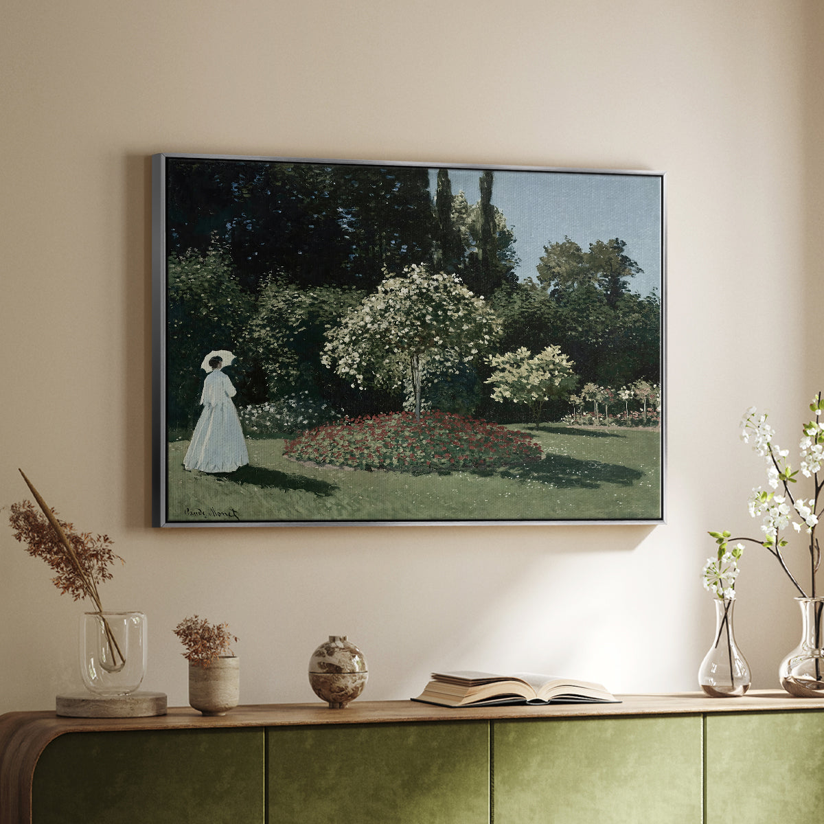 Silver floater framed canvas of Woman in the Garden, Sainte-Adresse, 1867 by Claude Monet, featuring an impressionist figure in sunlit garden with lush vegetation above a sideboard in a softly lit hallway.