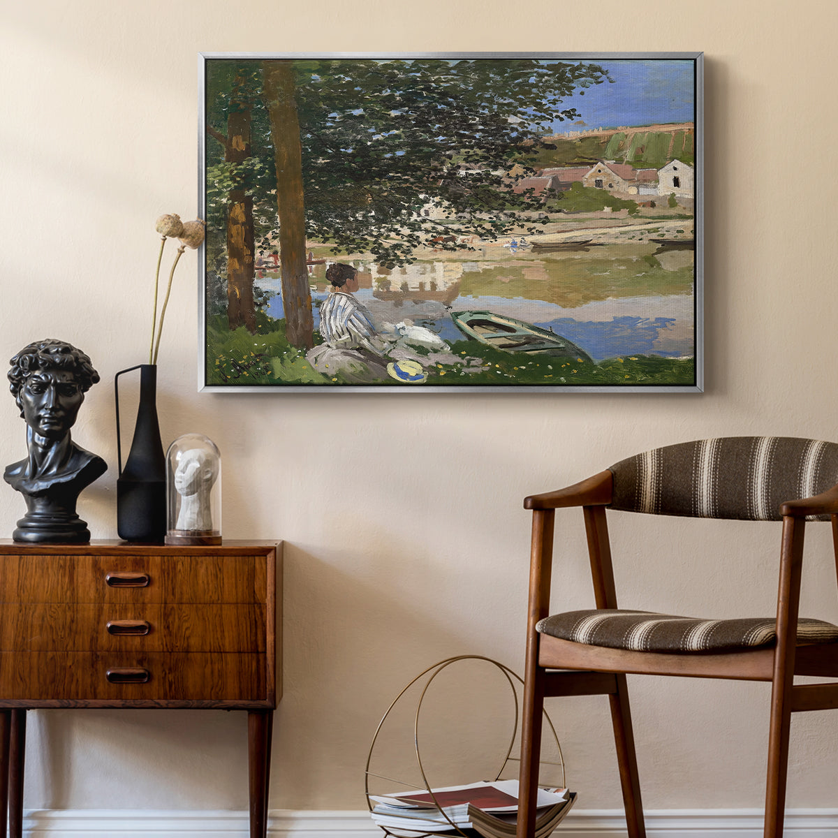 On the Bank of the Seine, Bennecourt, 1868 by Claude Monet as a silver floater framed canvas featuring an impressionist landscape with people relaxing along the Seine, styled above a mid-century console in a contemporary living area.