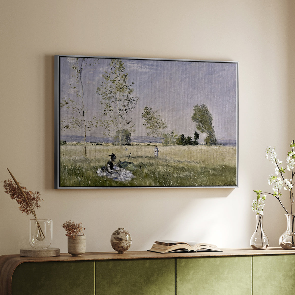 Silver floater framed canvas of Summer (L'ete), 1874 by Claude Monet, featuring an impressionist countryside scene with figure resting in shade above a sideboard in a softly lit hallway.