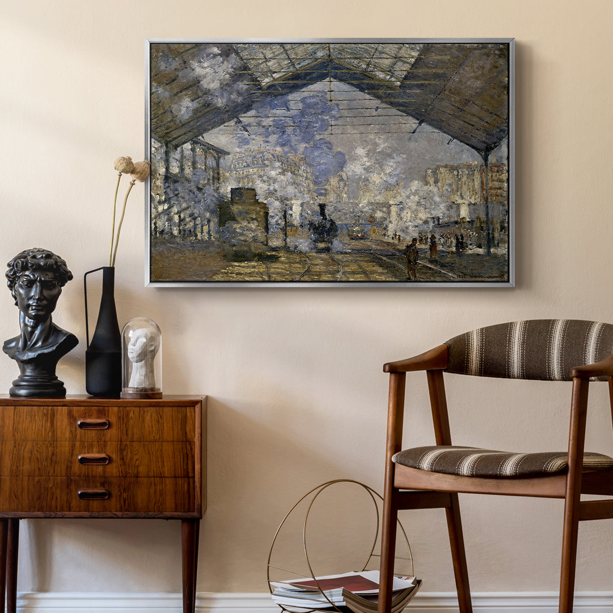 The Gare Saint-Lazare, 1877 by Claude Monet as a silver floater framed canvas featuring an industrial interior with steam clouds and rail tracks, styled above a mid-century console in a contemporary living area.