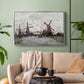 Silver floater framed canvas featuring a landscape featuring windmills and low horizon sky, displayed above a sofa in a modern living room.