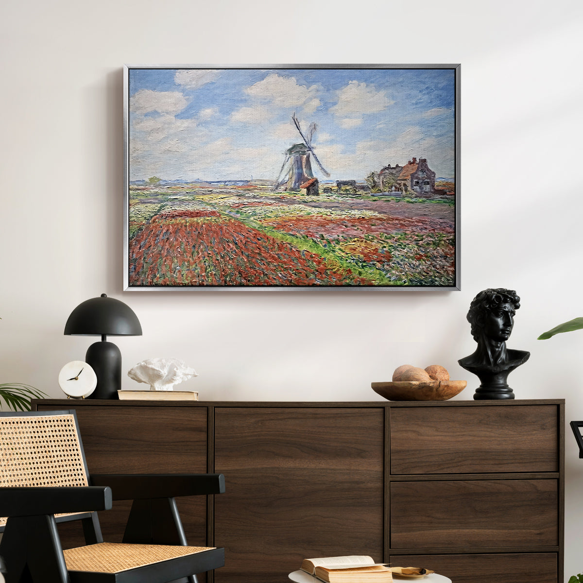 Tulip Fields with the Rijnsburg Windmill, 1886 by Claude Monet displayed in a silver floater framed canvas above a dark wood credenza in an entryway.