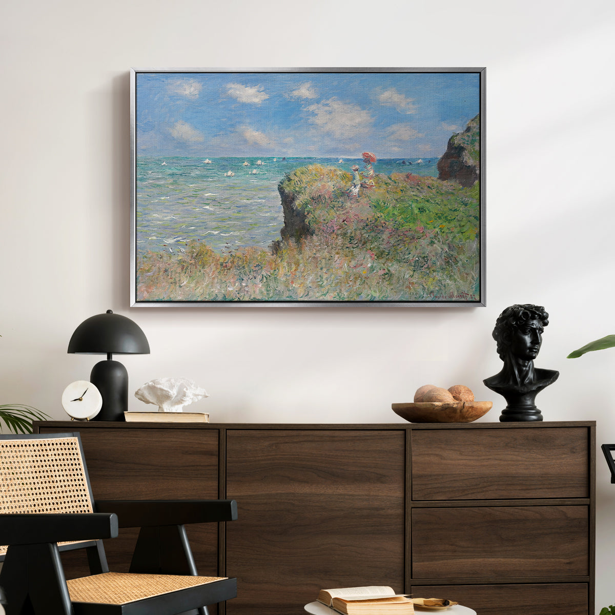 The Cliff Walk at Pourville, 1882 by Claude Monet displayed in a silver floater framed canvas above a dark wood credenza in an entryway.