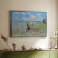 Silver floater framed canvas of The Cliff Walk at Pourville, 1882 by Claude Monet, featuring an impressionist seaside landscape with people strolling above water above a sideboard in a softly lit hallway.