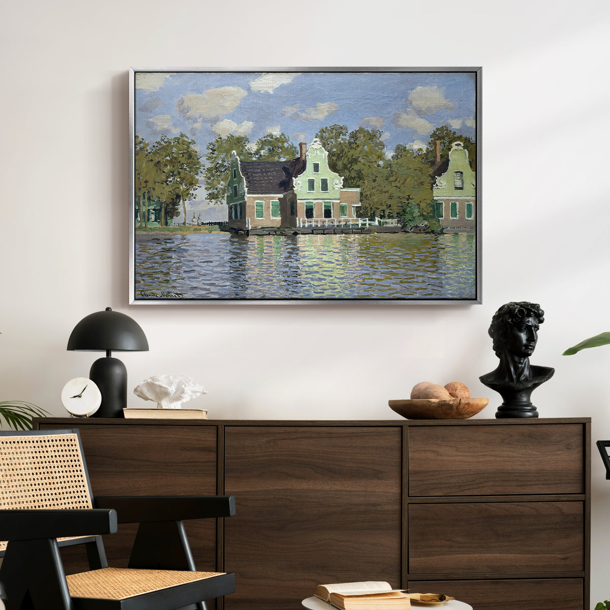 Houses on the Zaan River at Zaandam, 1871 by Claude Monet displayed in a silver floater framed canvas above a dark wood credenza in an entryway.