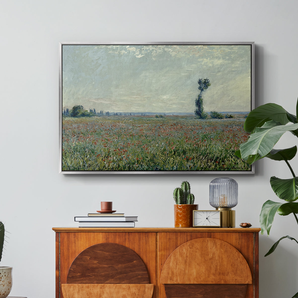 Poppy Field, 1881 by Claude Monet in a silver floater framed canvas featuring a wide field of red poppies stretching across countryside under open sky, displayed above a wood console cabinet.