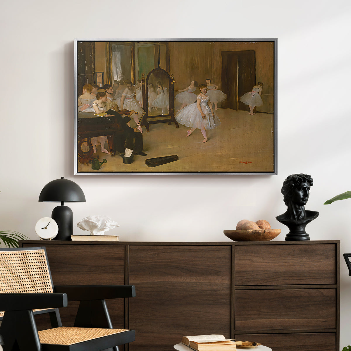 The Dancing Class, c. 1870 by Edgar Degas displayed in a silver floater framed canvas above a dark wood credenza in an entryway.