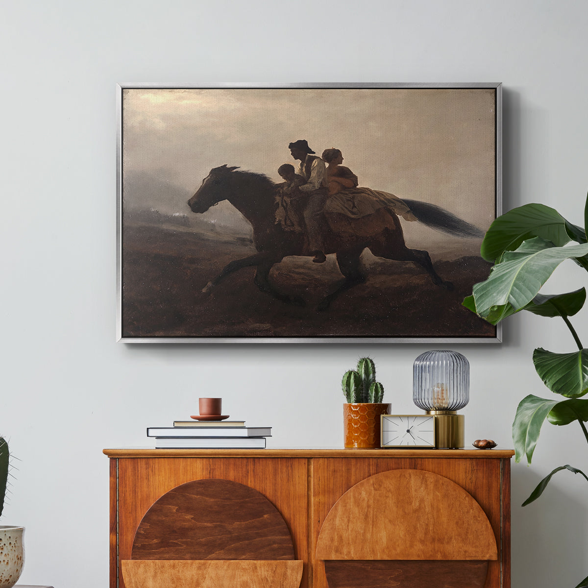 A Ride for Liberty – The Fugitive Slaves, c. 1862 by Eastman Johnson in a silver floater framed canvas featuring a family riding horseback through night escaping across landscape, displayed above a wood console cabinet.