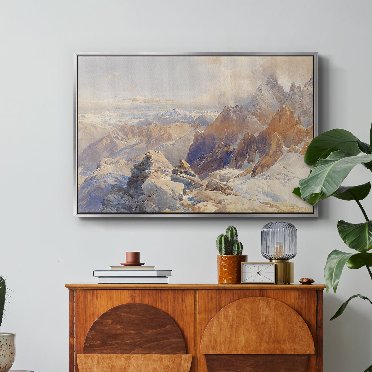 Col du Géant, 1903 by Edward Theodore Compton in a silver floater framed canvas featuring a mountain pass with snow-covered peaks and expansive alpine valley, displayed above a wood console cabinet.