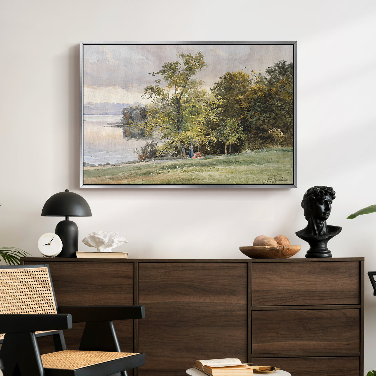 Landscape at Lake Starnberg, 1890 by Edward Theodore Compton displayed in a silver floater framed canvas above a dark wood credenza in an entryway.