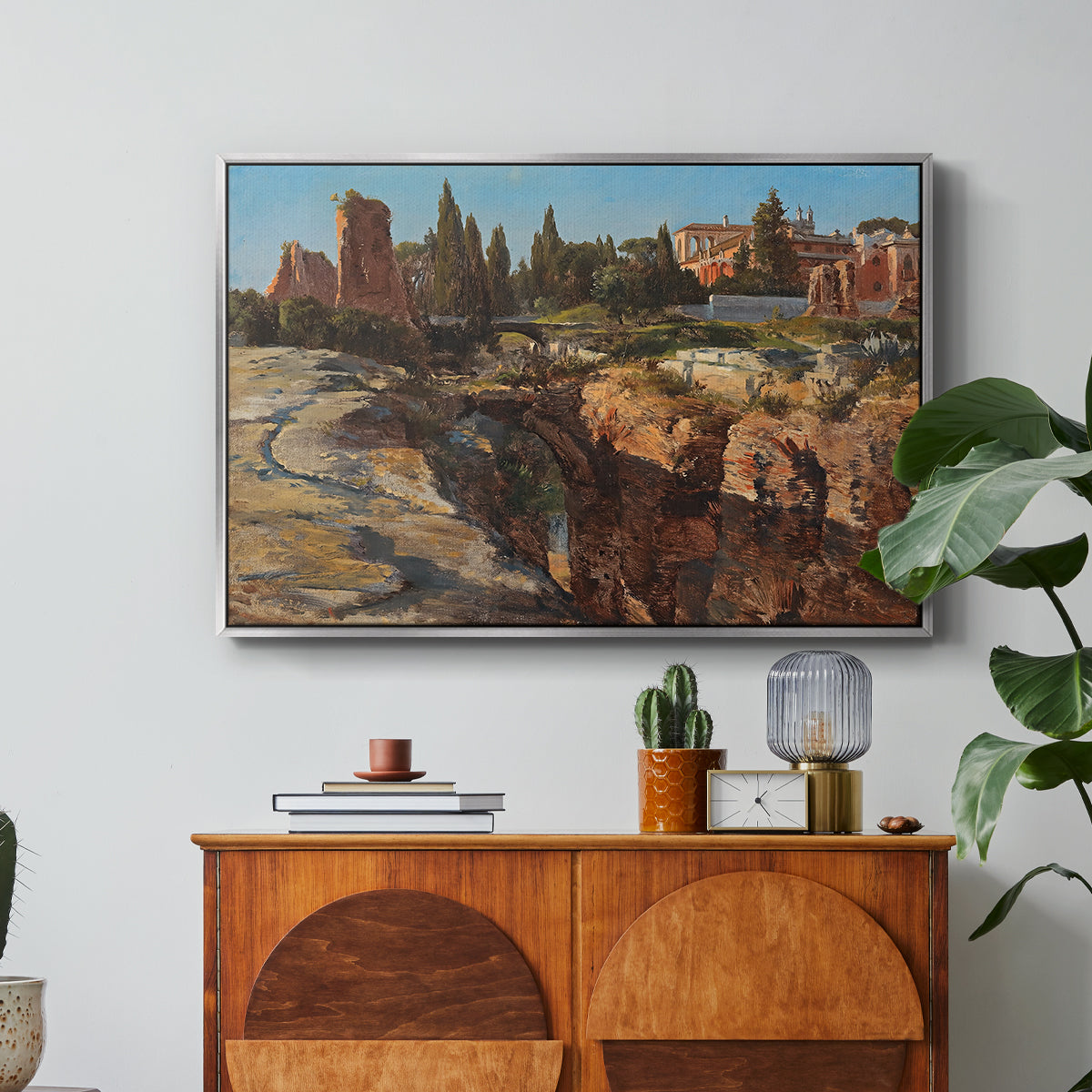 Palatine in Rome, c. 1921 by Edward Theodore Compton in a silver floater framed canvas featuring historic Roman ruins and buildings set within warm landscape, displayed above a wood console cabinet.