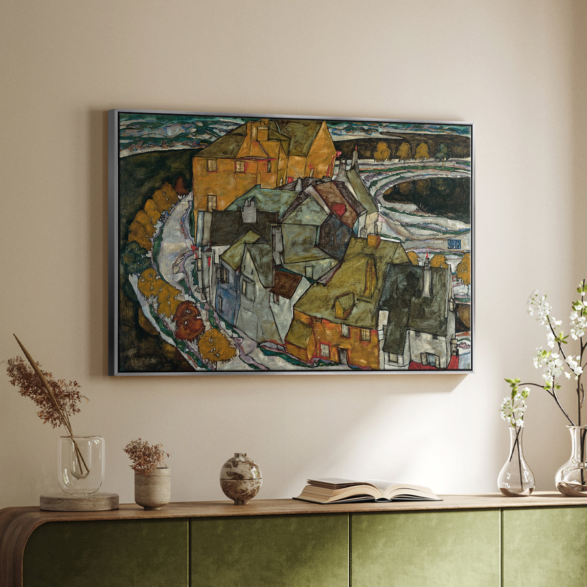 Silver floater framed canvas of Crescent of Houses II (Island Town), 1915 by Egon Schiele, featuring a stylized townscape with clustered buildings and bold outlines above a sideboard in a softly lit hallway.