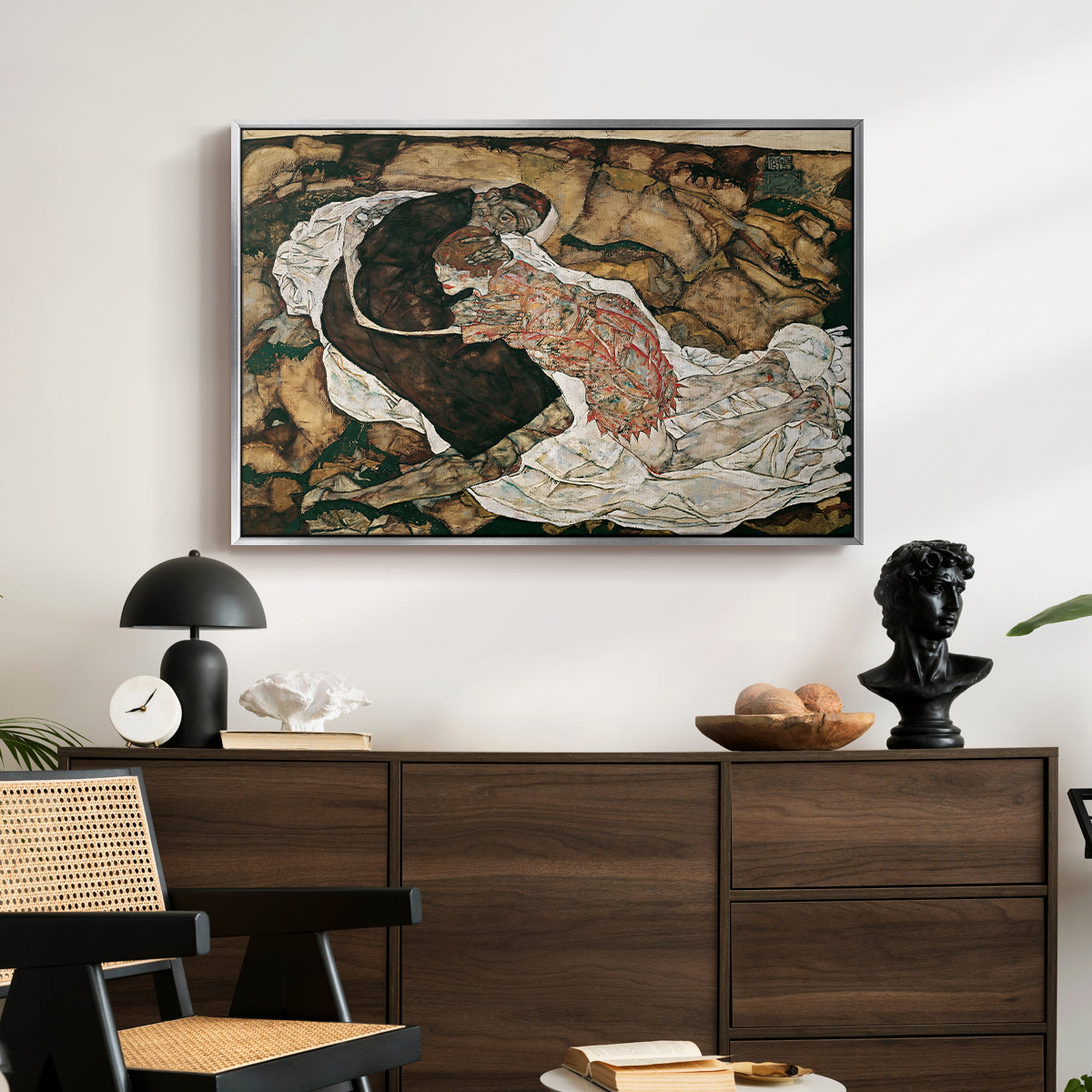 Death and the Maiden, 1915 by Egon Schiele displayed in a silver floater framed canvas above a dark wood credenza in an entryway.