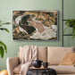 Silver floater framed canvas featuring an intense composition exploring life and death through figures, displayed above a sofa in a modern living room.