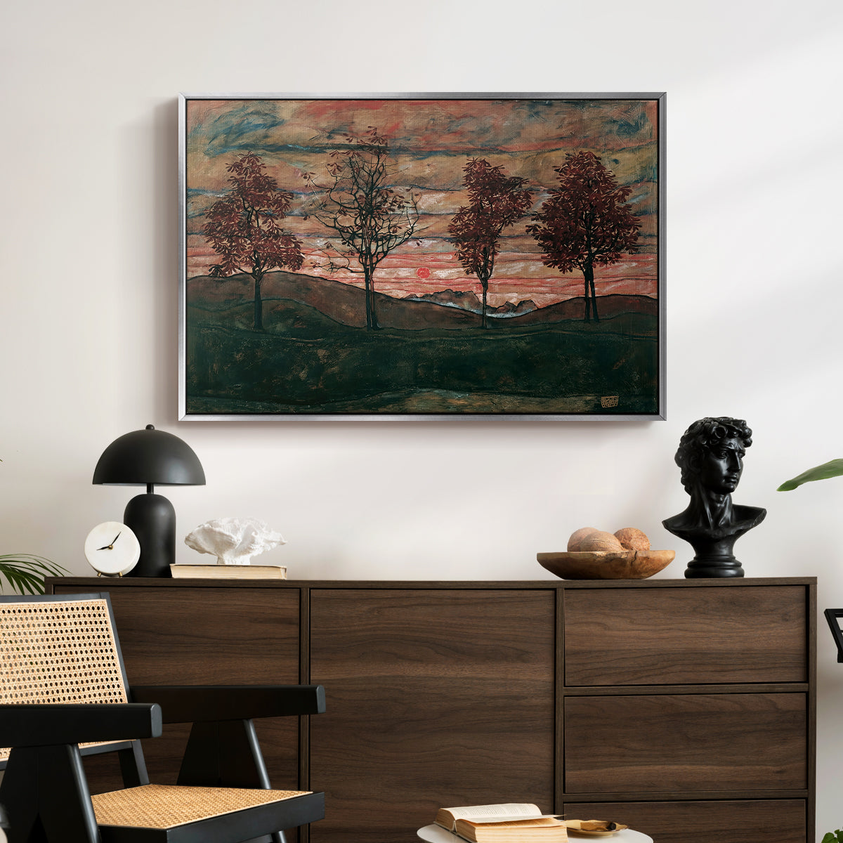 Four Trees, 1917 by Egon Schiele displayed in a silver floater framed canvas above a dark wood credenza in an entryway.