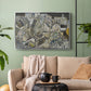 Silver floater framed canvas featuring a stylized urban composition with geometric structures and muted tones, displayed above a sofa in a modern living room.