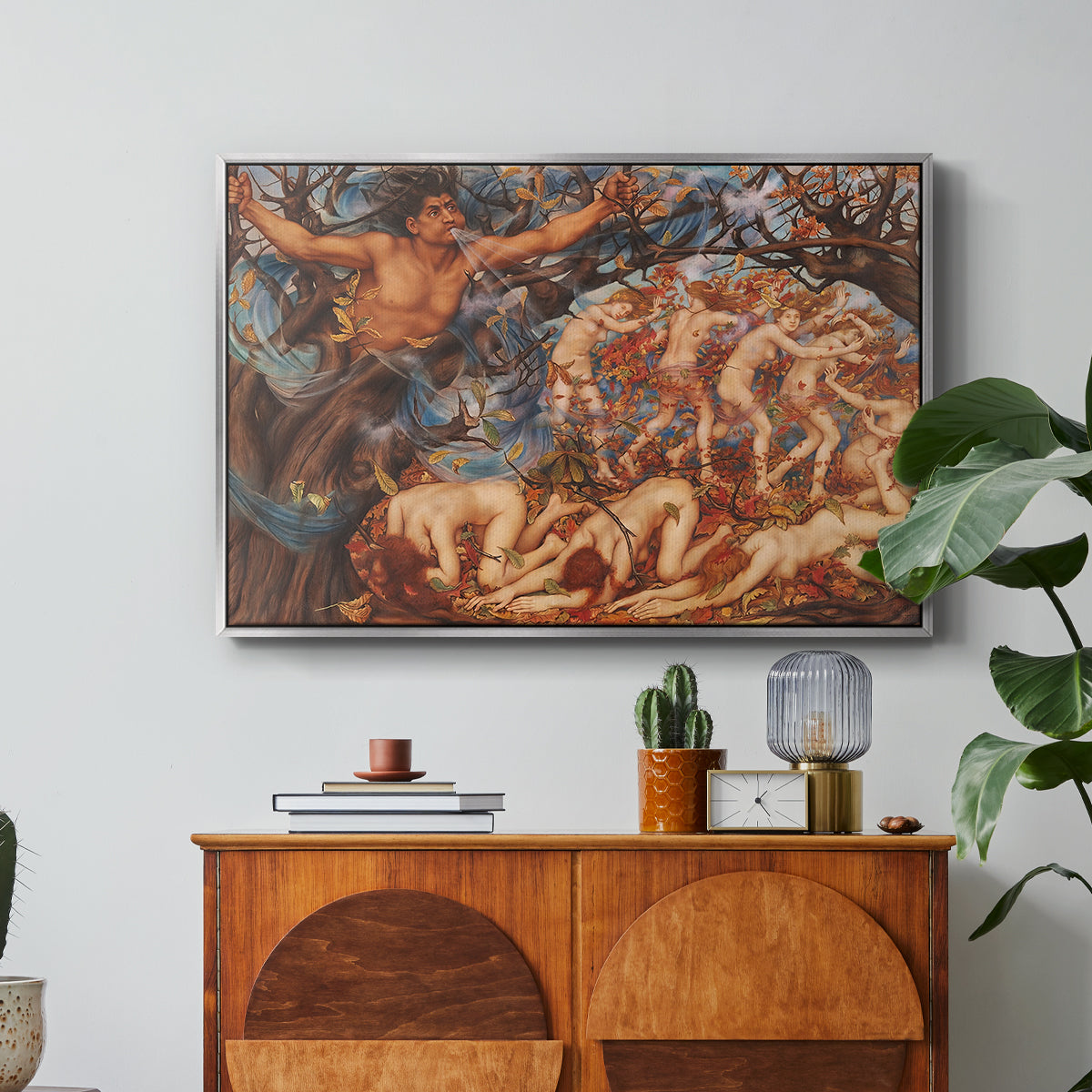 Boreas and the Fallen Leaves, c. 1910-1914 by Evelyn De Morgan in a silver floater framed canvas featuring swirling figures carried by wind among falling leaves in dynamic composition, displayed above a wood console cabinet.