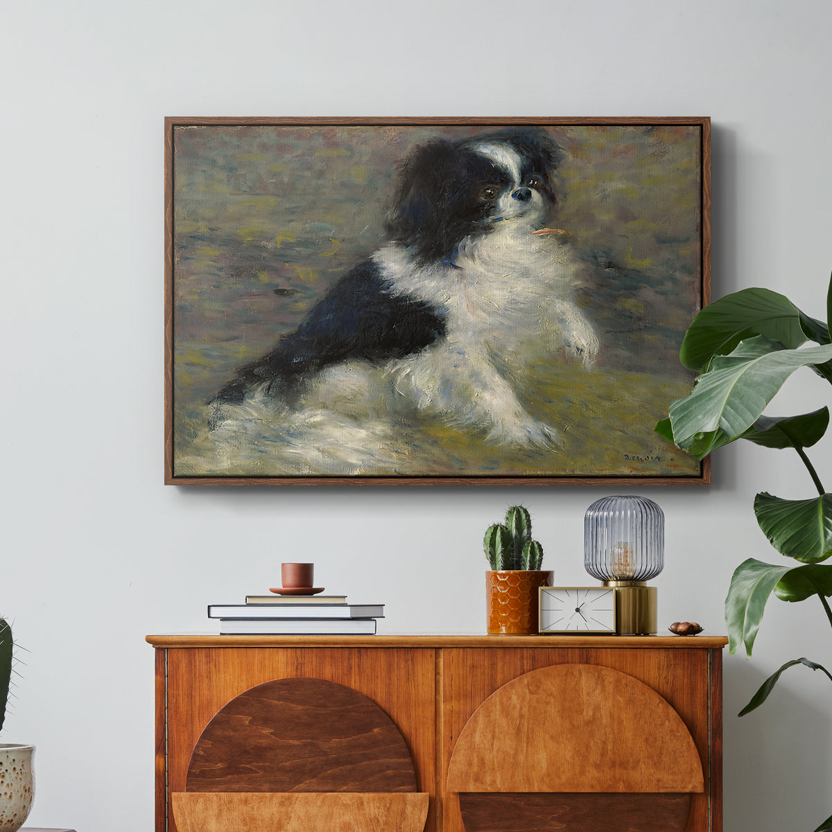 Tama, the Japanese Dog, c. 1876 by Pierre-Auguste Renoir in a walnut floater framed canvas featuring a small black and white dog standing in shallow water with soft brushstrokes, displayed above a wood console cabinet.
