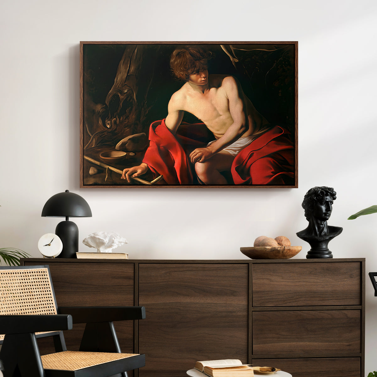 Saint John the Baptist in the Wilderness, c. 1603-1604 by Caravaggio displayed in a walnut floater framed canvas above a dark wood credenza in an entryway.