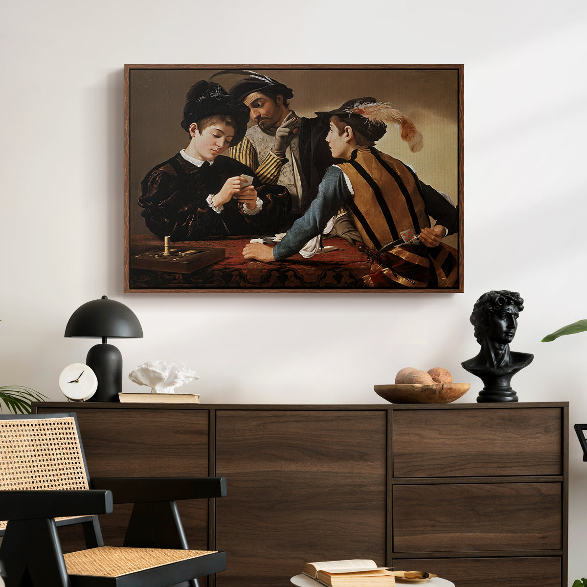 The Cardsharps, c. 1594 by Caravaggio displayed in a walnut floater framed canvas above a dark wood credenza in an entryway.