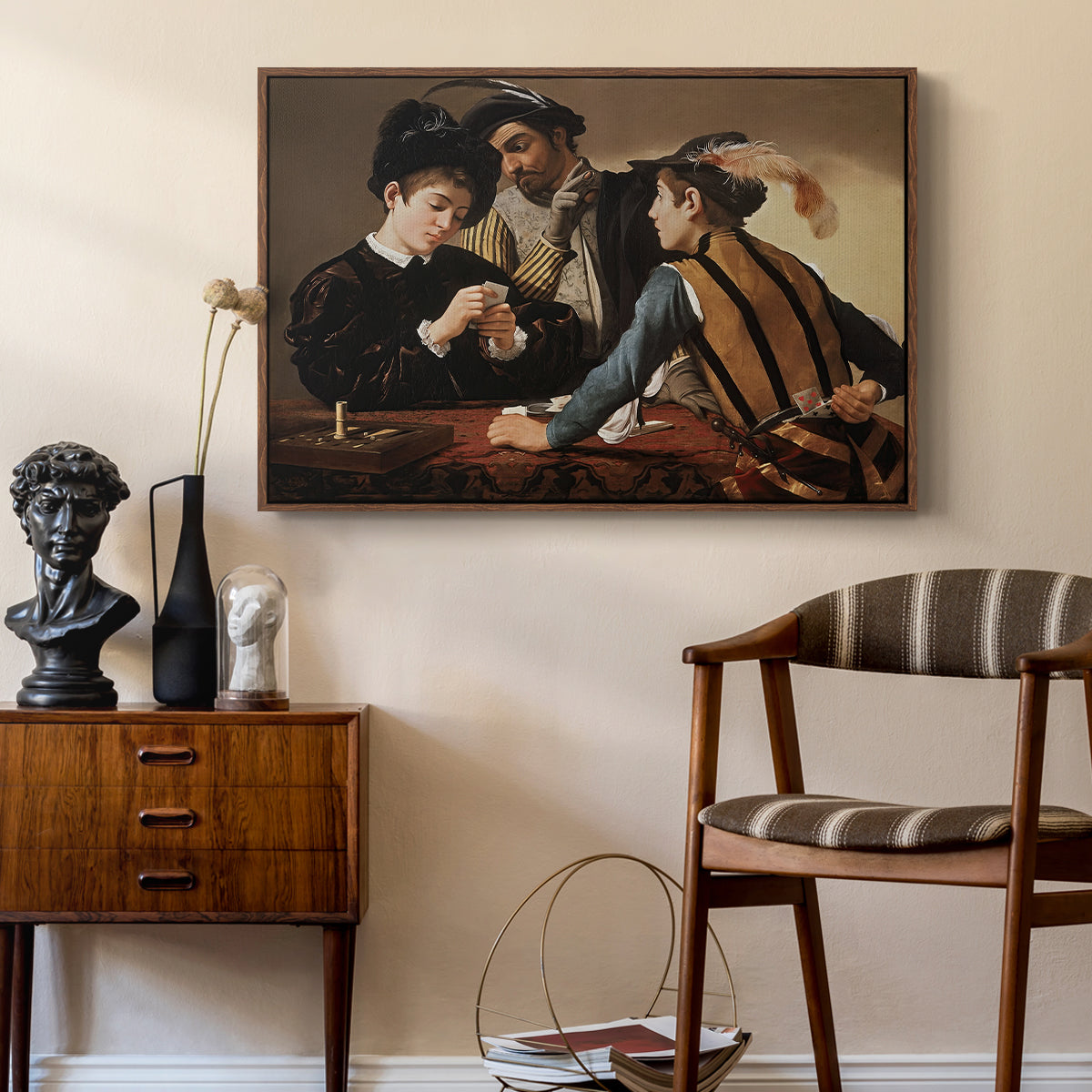 The Cardsharps, c. 1594 by Caravaggio as a walnut floater framed canvas featuring a young men playing cards with one cheating and another watching closely, styled above a mid-century console in a contemporary living area.