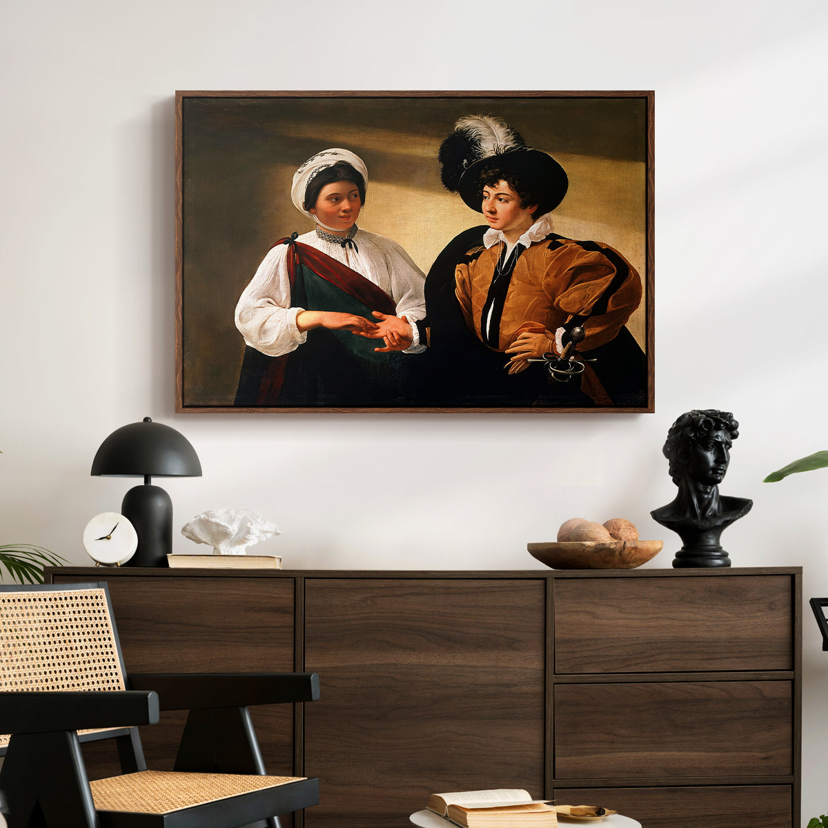 The Fortune Teller (Louvre Version), c. 1595 by Caravaggio displayed in a walnut floater framed canvas above a dark wood credenza in an entryway.