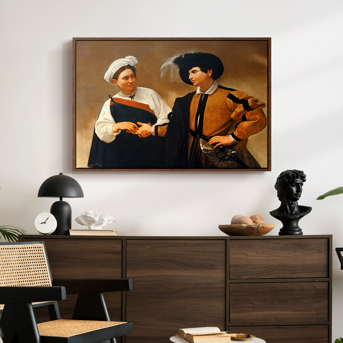 The Fortune Teller (Capitoline Version), c. 1599 by Caravaggio displayed in a walnut floater framed canvas above a dark wood credenza in an entryway.