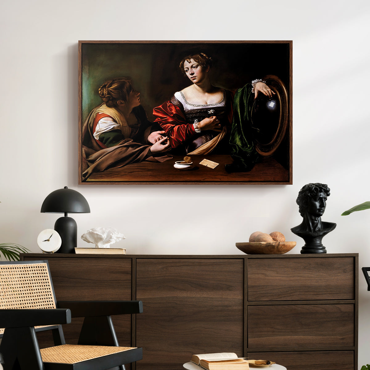 Martha and Mary Magdalene, c. 1598 by Caravaggio displayed in a walnut floater framed canvas above a dark wood credenza in an entryway.