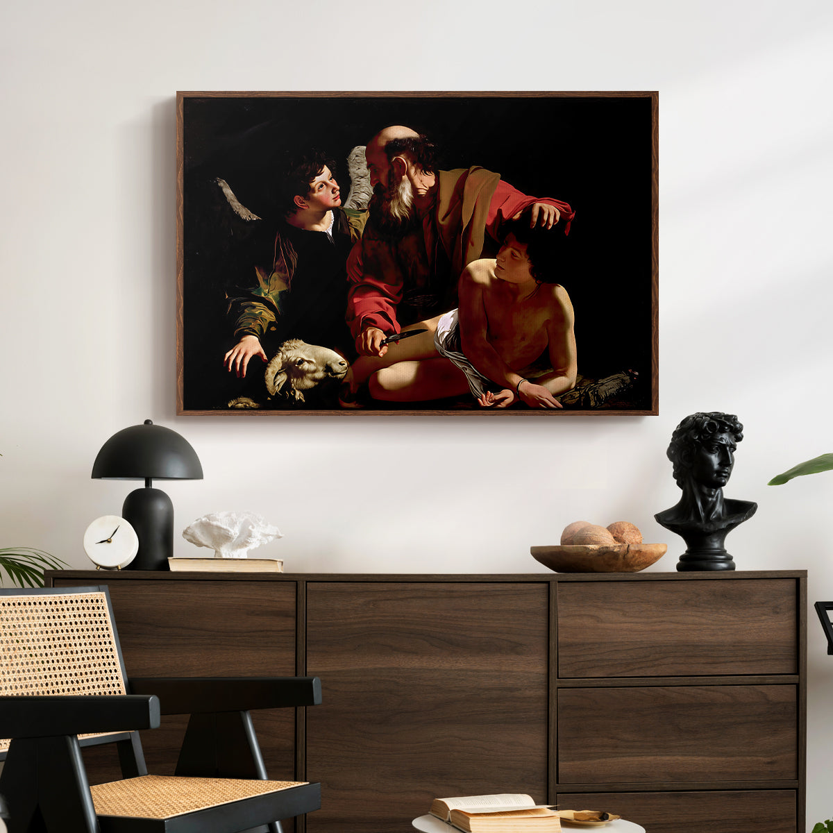 The Sacrifice of Isaac (Uffizi Version), c. 1603 by Caravaggio displayed in a walnut floater framed canvas above a dark wood credenza in an entryway.