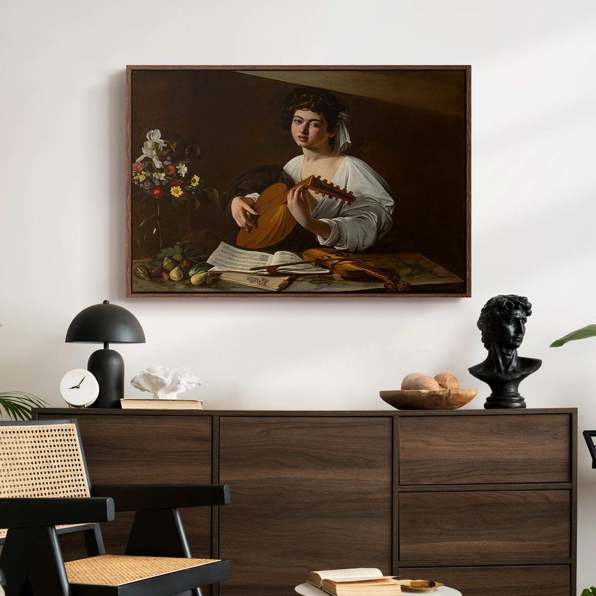 The Lute Player (Hermitage Version), c. 1596 by Caravaggio displayed in a walnut floater framed canvas above a dark wood credenza in an entryway.