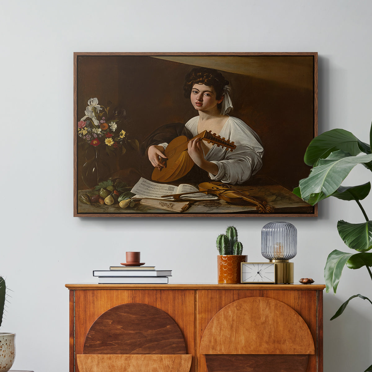 The Lute Player (Hermitage Version), c. 1596 by Caravaggio in a walnut floater framed canvas featuring a young musician playing lute beside table with fruit and sheet music, displayed above a wood console cabinet.
