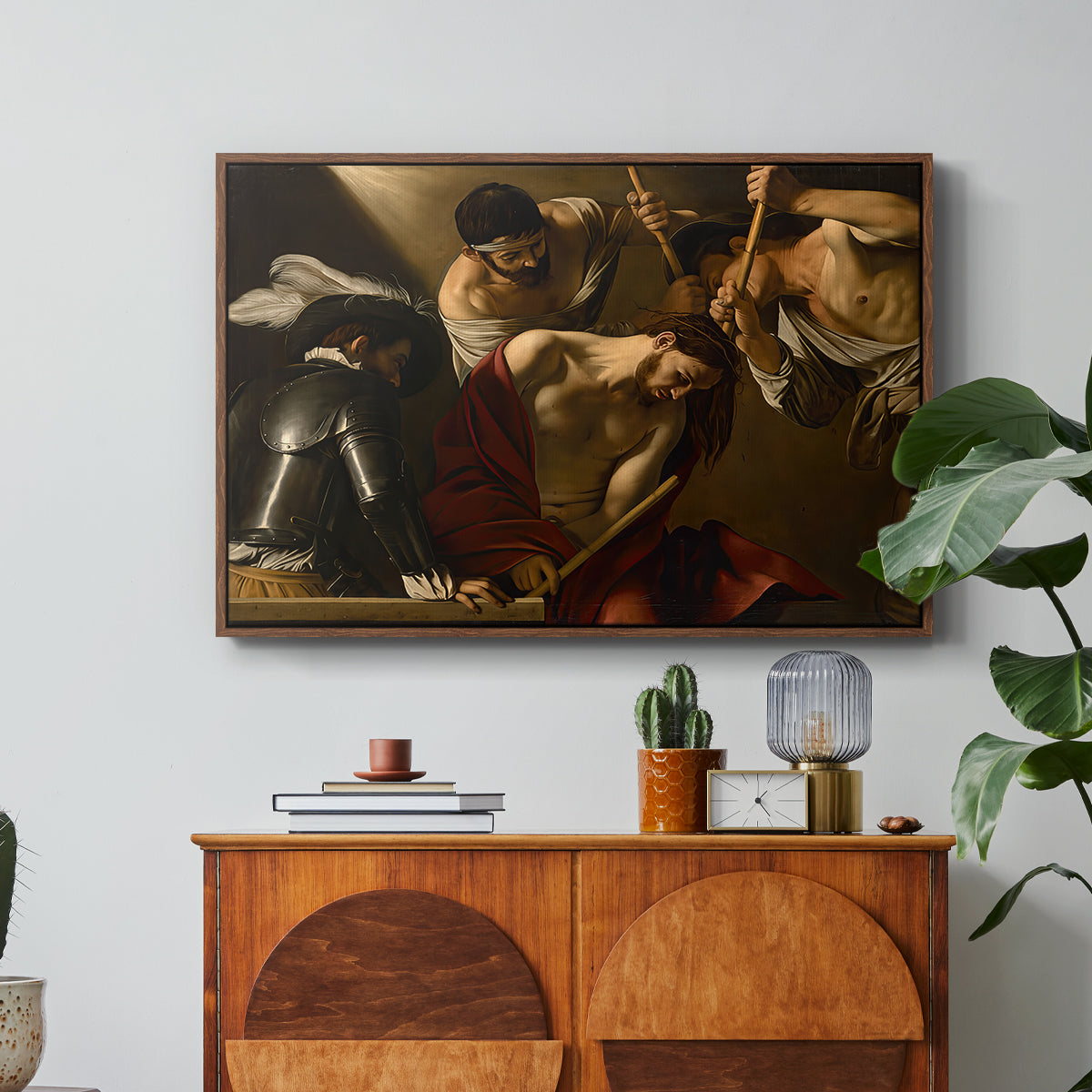 The Crowning with Thorns (Vienna Version), c. 1602-1604 by Caravaggio in a walnut floater framed canvas featuring Christ surrounded by men pressing crown of thorns onto his head, displayed above a wood console cabinet.