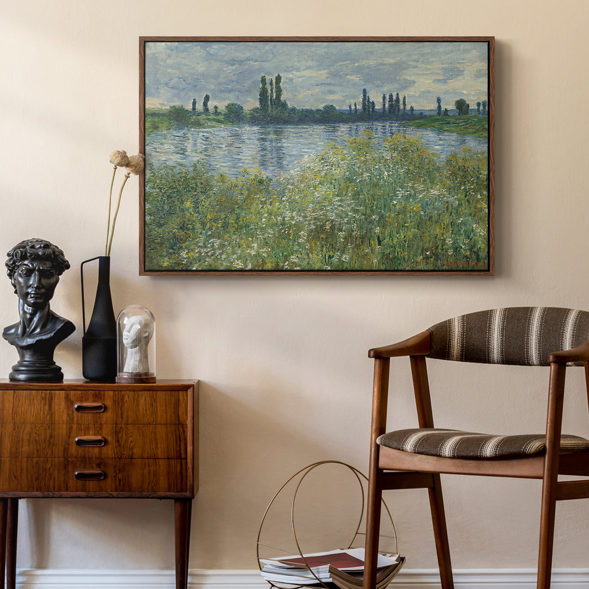 Banks of the Seine, Vétheuil, 1880 by Claude Monet as a walnut floater framed canvas featuring a tranquil riverside scene with houses and vegetation, styled above a mid-century console in a contemporary living area.