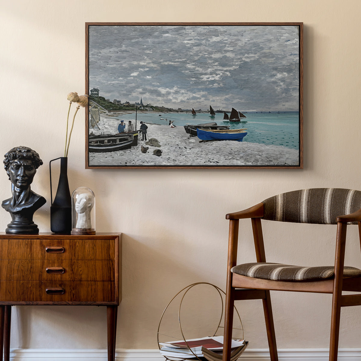 The Beach at Sainte-Adresse, 1867 by Claude Monet as a walnut floater framed canvas featuring a coastal landscape with sailboats and visitors on cliffside, styled above a mid-century console in a contemporary living area.
