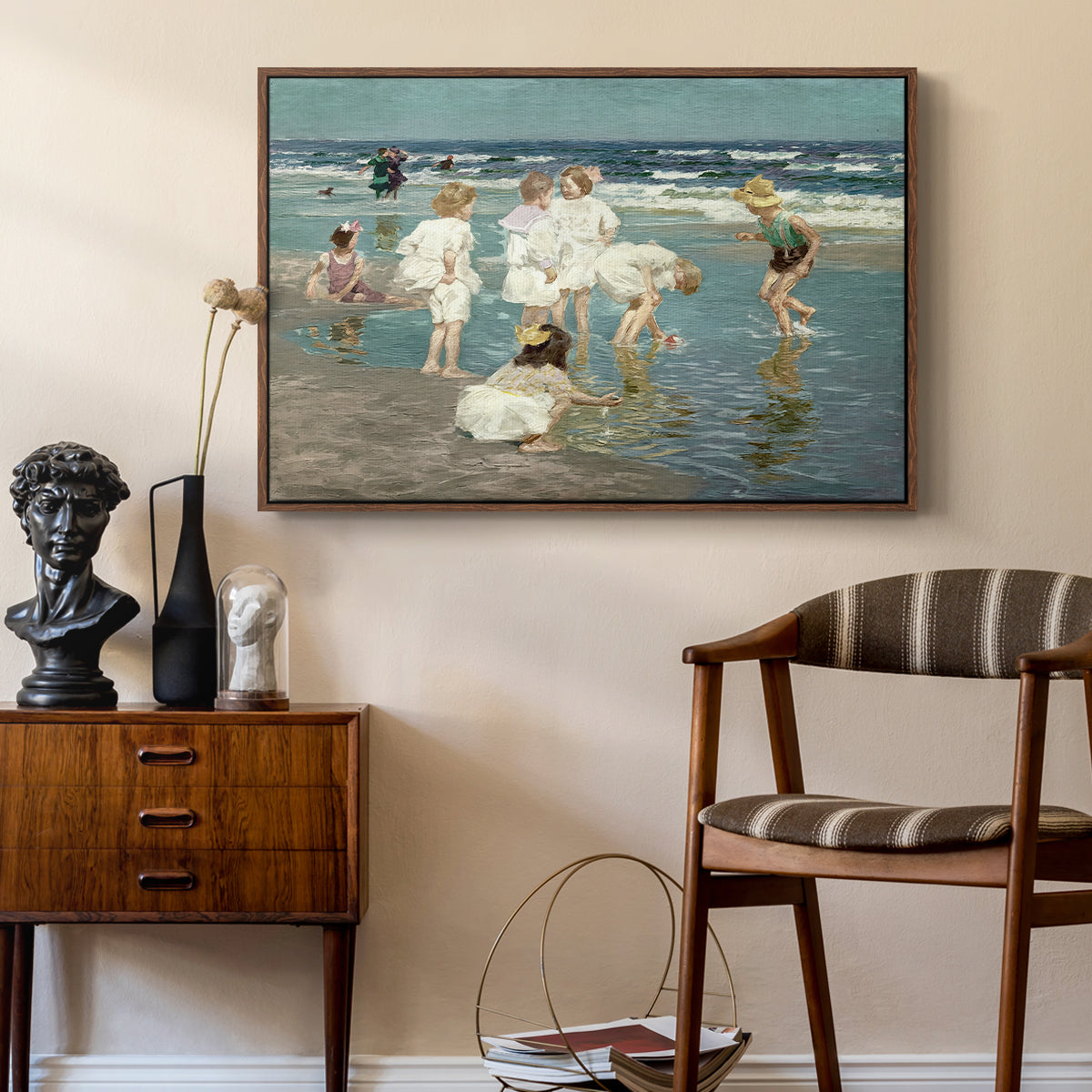 A Holiday, c. 1915 by Edward Henry Potthast as a walnut floater framed canvas featuring an impressionist coastal view of families enjoying seaside water, styled above a mid-century console in a contemporary living area.