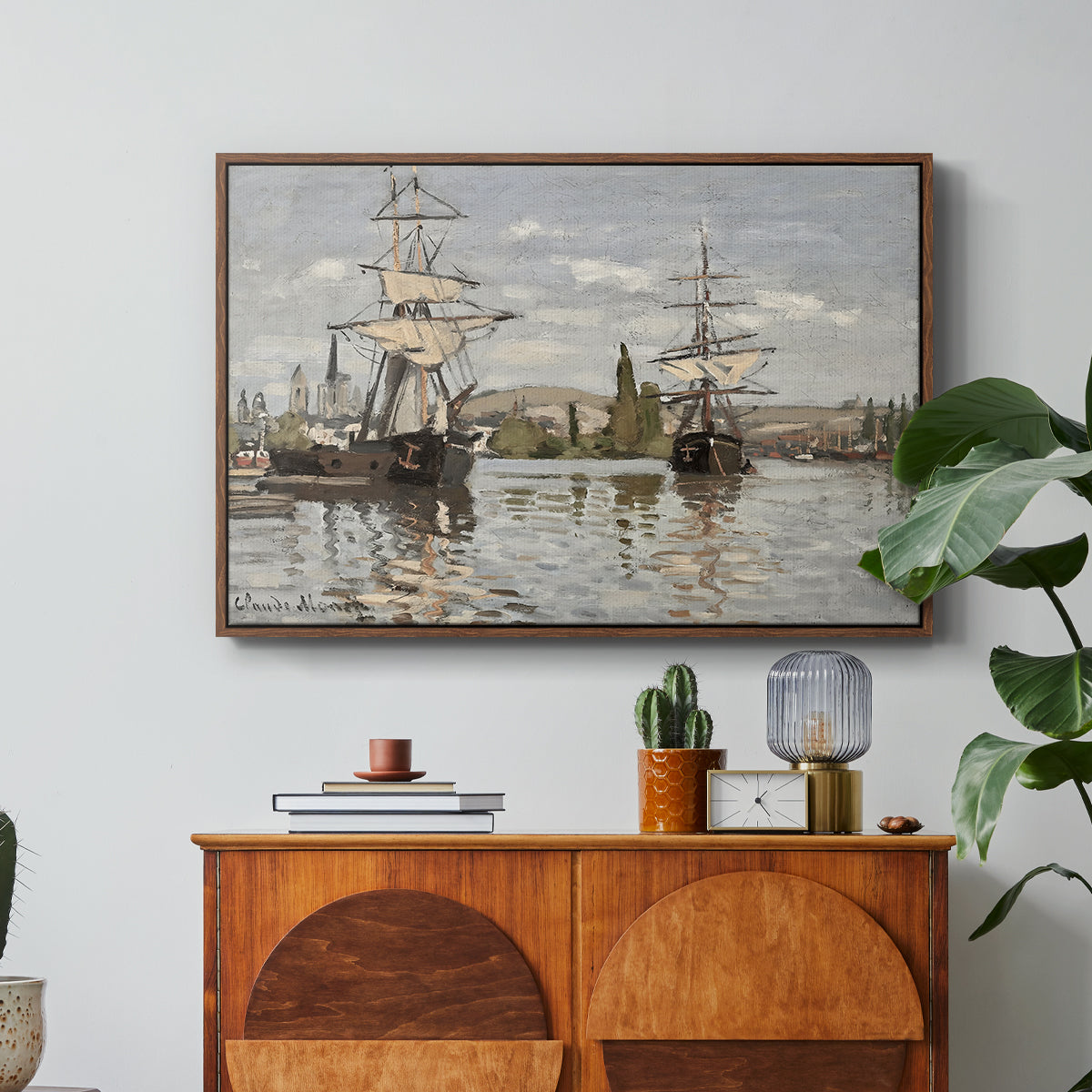 Ships Riding on the Seine at Rouen, 1872 by Claude Monet in a walnut floater framed canvas featuring large ships docked along the Seine with masts rising against soft sky, displayed above a wood console cabinet.