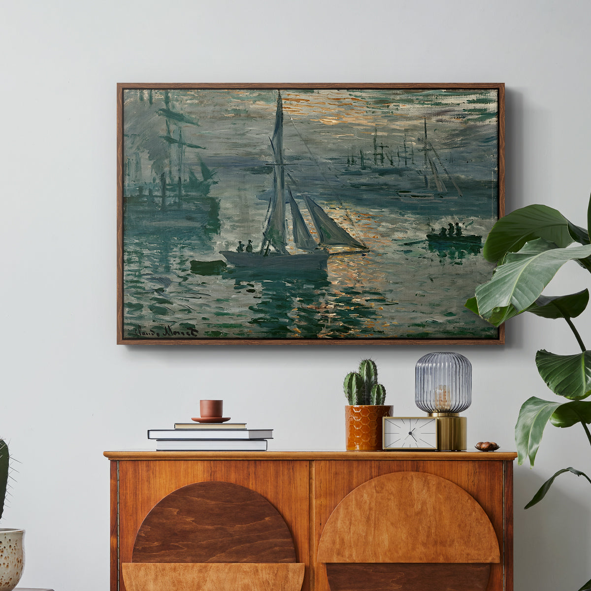 Sunrise (Marine), 1873 by Claude Monet in a walnut floater framed canvas featuring a hazy sunrise over harbor with boats silhouetted in soft morning light, displayed above a wood console cabinet.