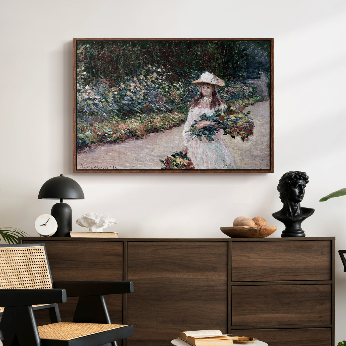 Young Girl in the Garden at Giverny, 1888 by Claude Monet displayed in a walnut floater framed canvas above a dark wood credenza in an entryway.
