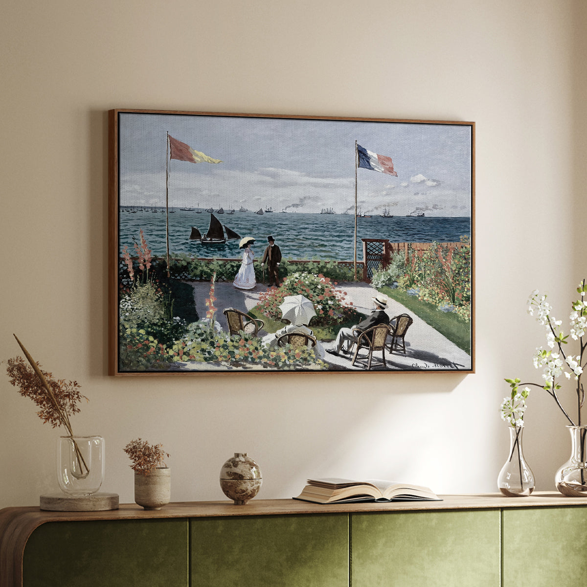 Walnut floater framed canvas of Garden at Sainte-Adresse, 1867 by Claude Monet, featuring an impressionist coastal garden with people and ocean view above a sideboard in a softly lit hallway.