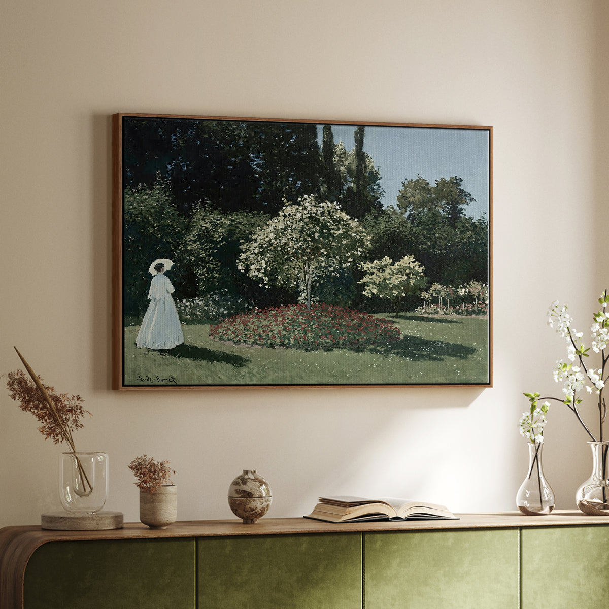 Walnut floater framed canvas of Woman in the Garden, Sainte-Adresse, 1867 by Claude Monet, featuring an impressionist figure in sunlit garden with lush vegetation above a sideboard in a softly lit hallway.