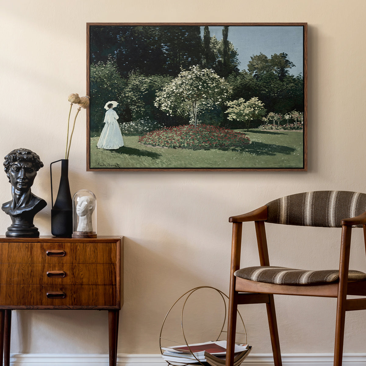 Woman in the Garden, Sainte-Adresse, 1867 by Claude Monet as a walnut floater framed canvas featuring an elegant woman posed outdoors among blooming plants, styled above a mid-century console in a contemporary living area.