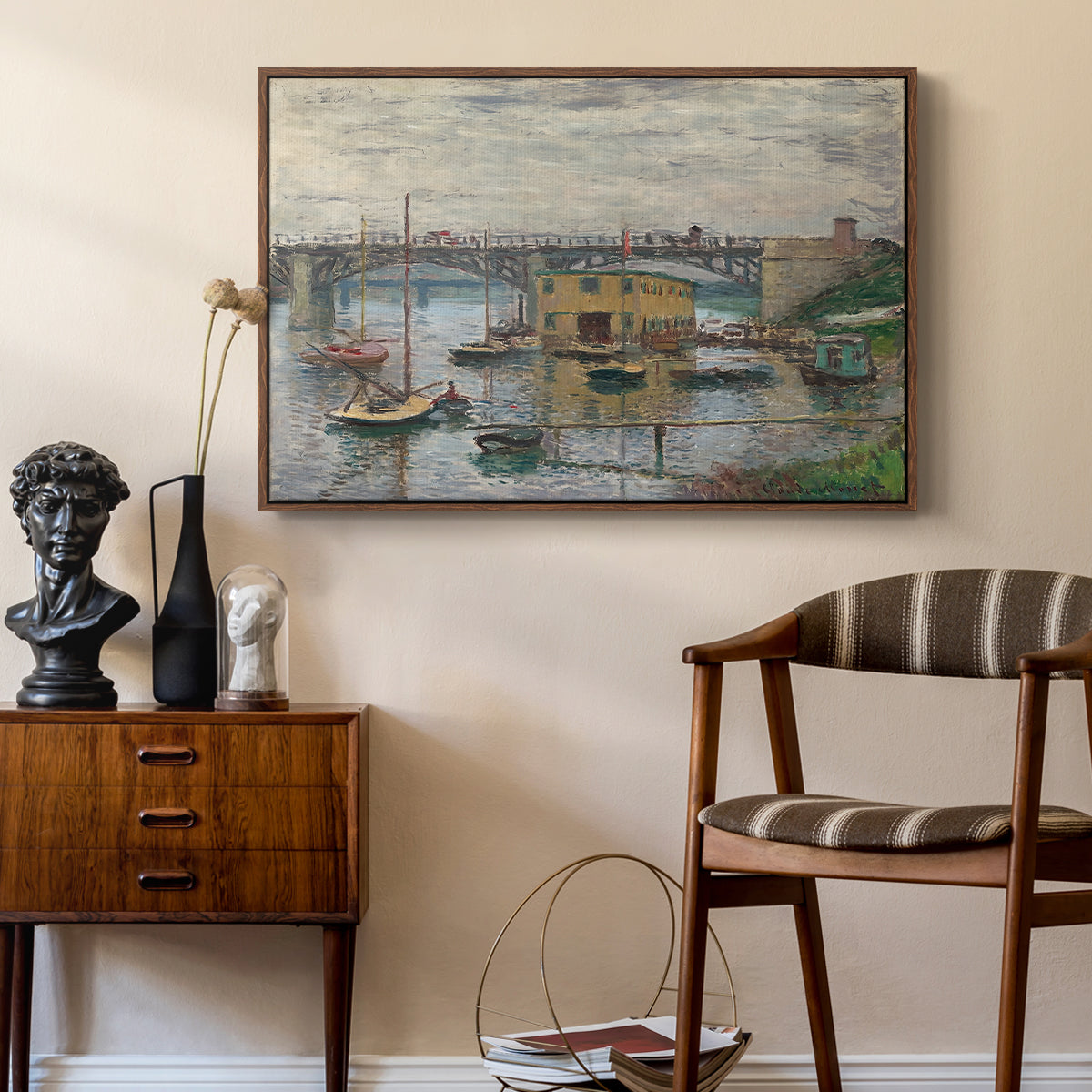 Bridge at Argenteuil on a Gray Day, c. 1876 by Claude Monet as a walnut floater framed canvas featuring a calm water scene with bridge fading into cloudy sky, styled above a mid-century console in a contemporary living area.