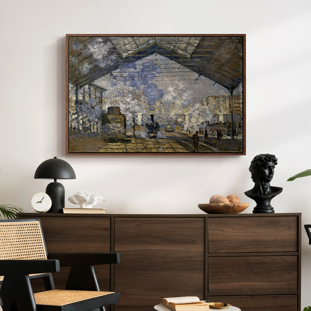The Gare Saint-Lazare, 1877 by Claude Monet displayed in a walnut floater framed canvas above a dark wood credenza in an entryway.