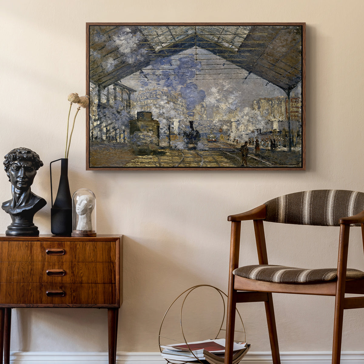 The Gare Saint-Lazare, 1877 by Claude Monet as a walnut floater framed canvas featuring an industrial interior with steam clouds and rail tracks, styled above a mid-century console in a contemporary living area.