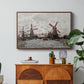 Windmills near Zaandam, 1871 by Claude Monet in a walnut floater framed canvas featuring windmills standing beside water under open sky in rural landscape, displayed above a wood console cabinet.
