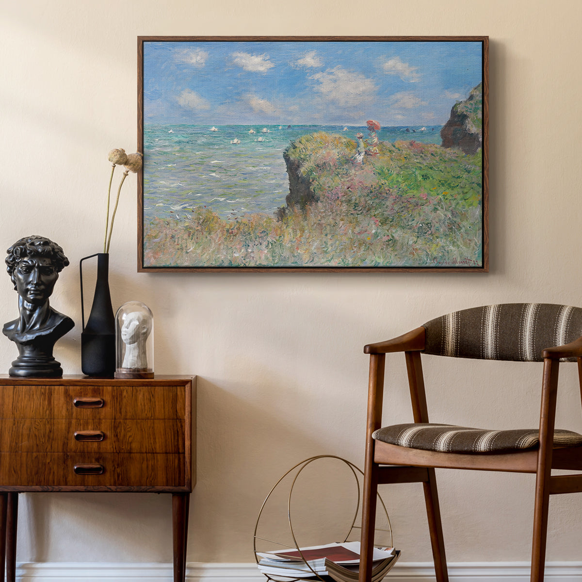 The Cliff Walk at Pourville, 1882 by Claude Monet as a walnut floater framed canvas featuring a coastal cliff scene with grass, wind, and expansive sea view, styled above a mid-century console in a contemporary living area.