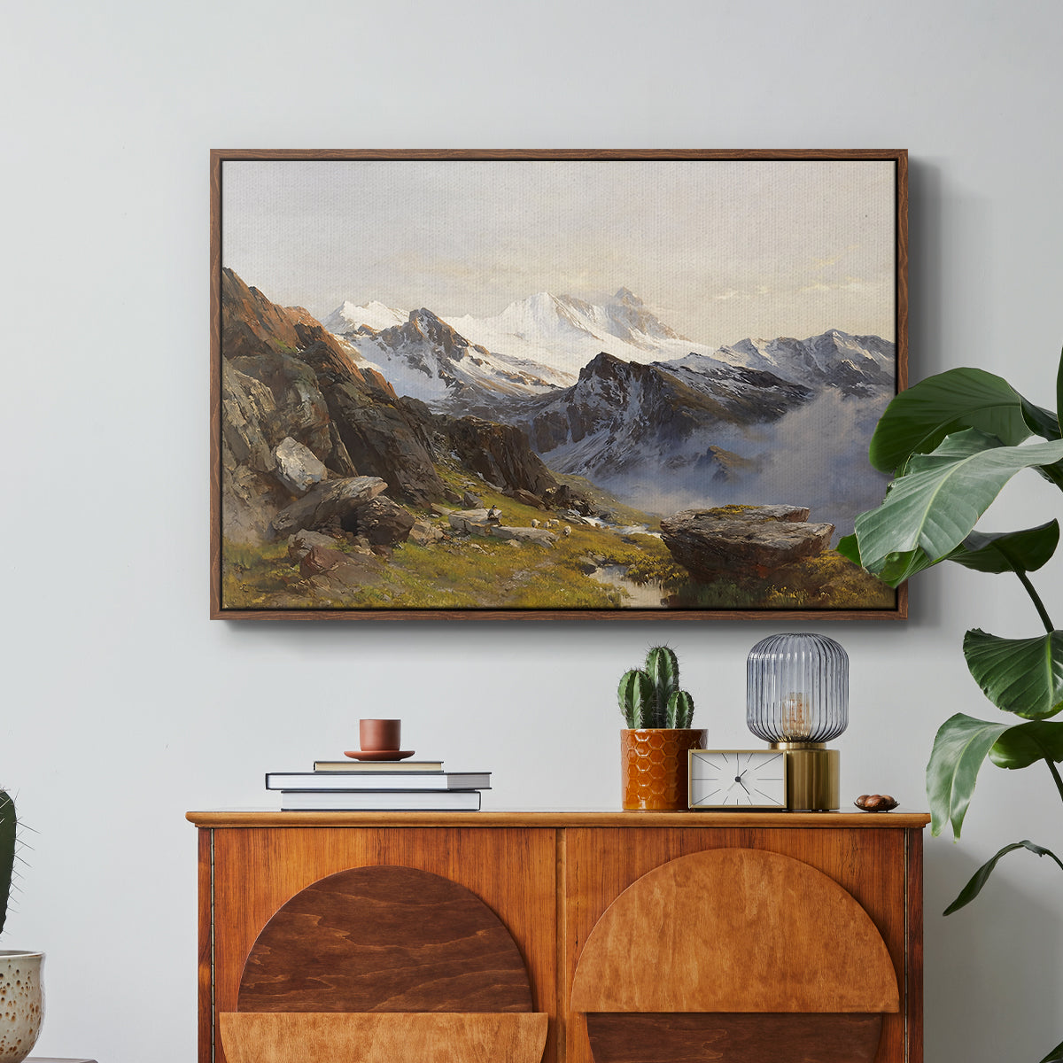 The Großglockner from the Prager Hut, 1890 by Edward Theodore Compton in a walnut floater framed canvas featuring a view of Großglockner peak from alpine hut overlooking valley, displayed above a wood console cabinet.