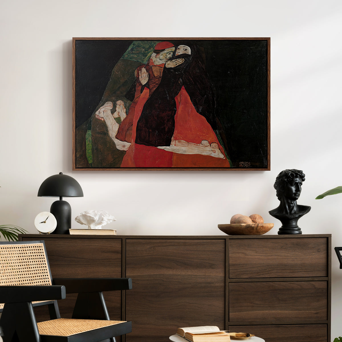Cardinal and Nun (Caress), 1912 by Egon Schiele displayed in a walnut floater framed canvas above a dark wood credenza in an entryway.