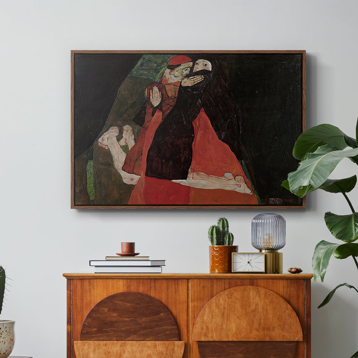 Cardinal and Nun (Caress), 1912 by Egon Schiele in a walnut floater framed canvas featuring two figures embracing intimately in stylized expressionist composition, displayed above a wood console cabinet.